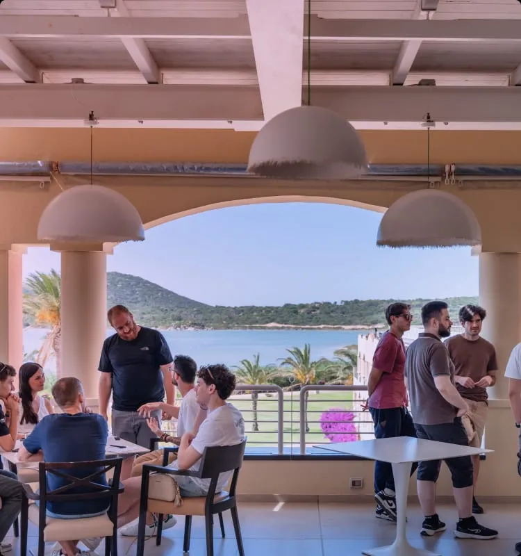 Colleghi che chiacchierano su una terrazza sul mare, accanto a un tavolo da ping pong