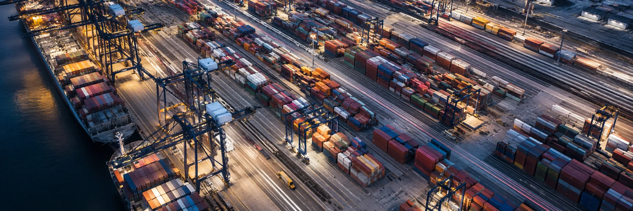 Vista aerea di un terminal intermodale con file di container e binari ferroviari.