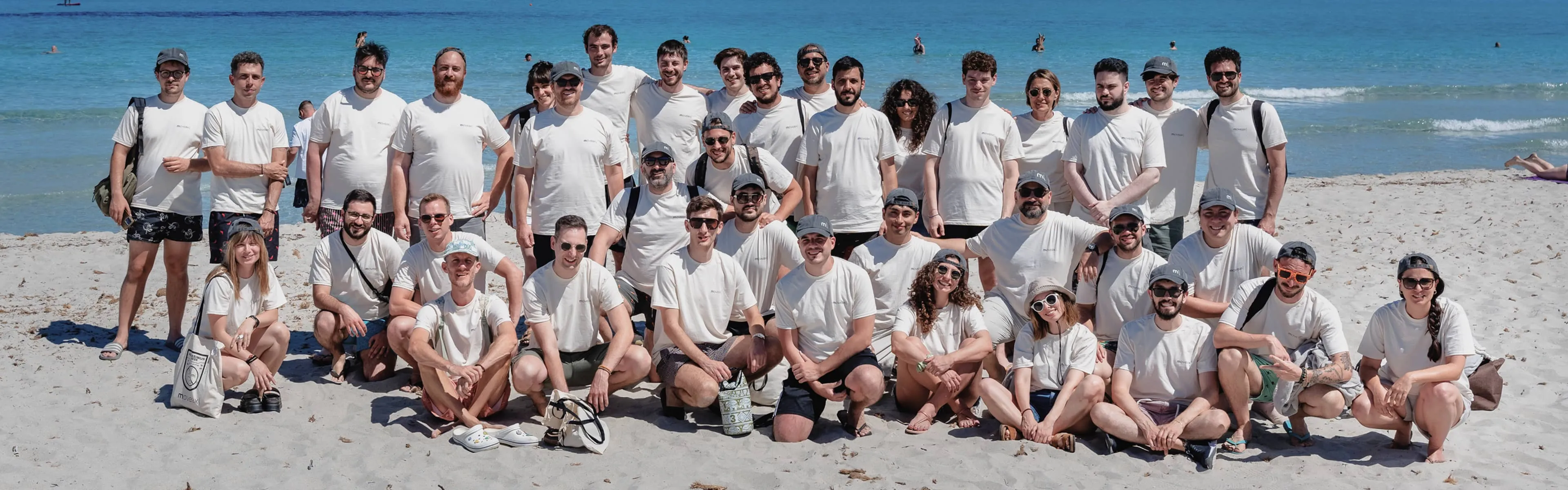 Il team di moveax in posa per una foto di gruppo su una spiaggia, durante il team building estivo.